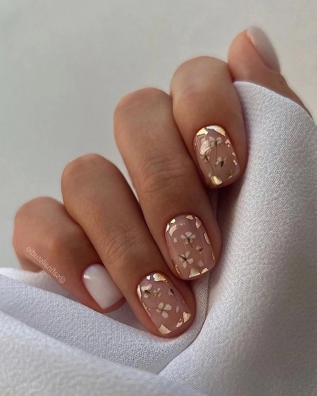 Soft nude oval nails with one warm brown floral accent