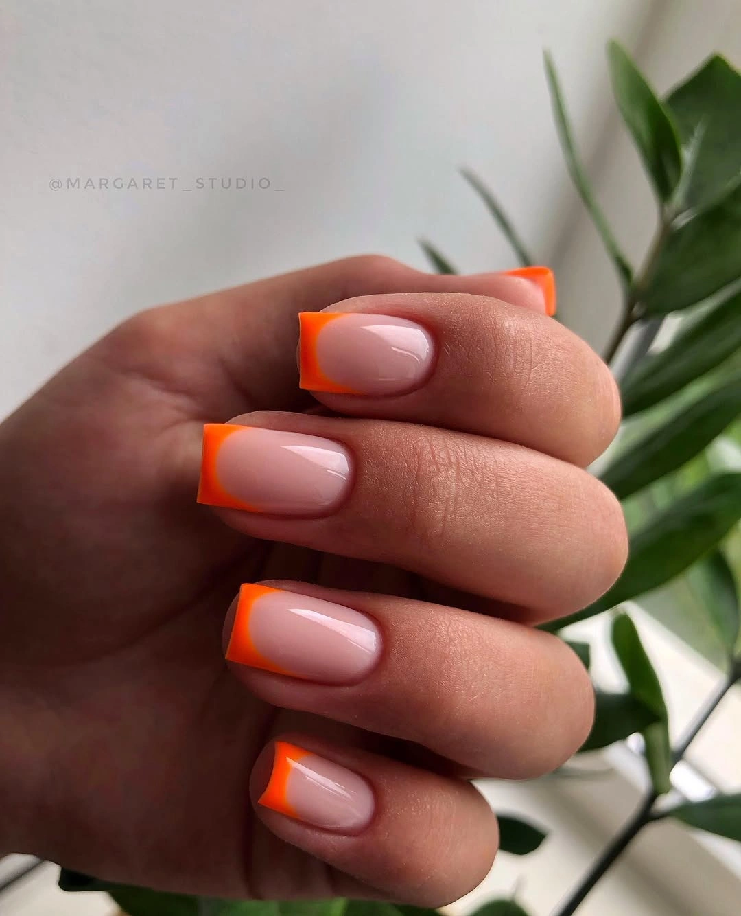 Medium square nude nails with vivid neon orange French tips