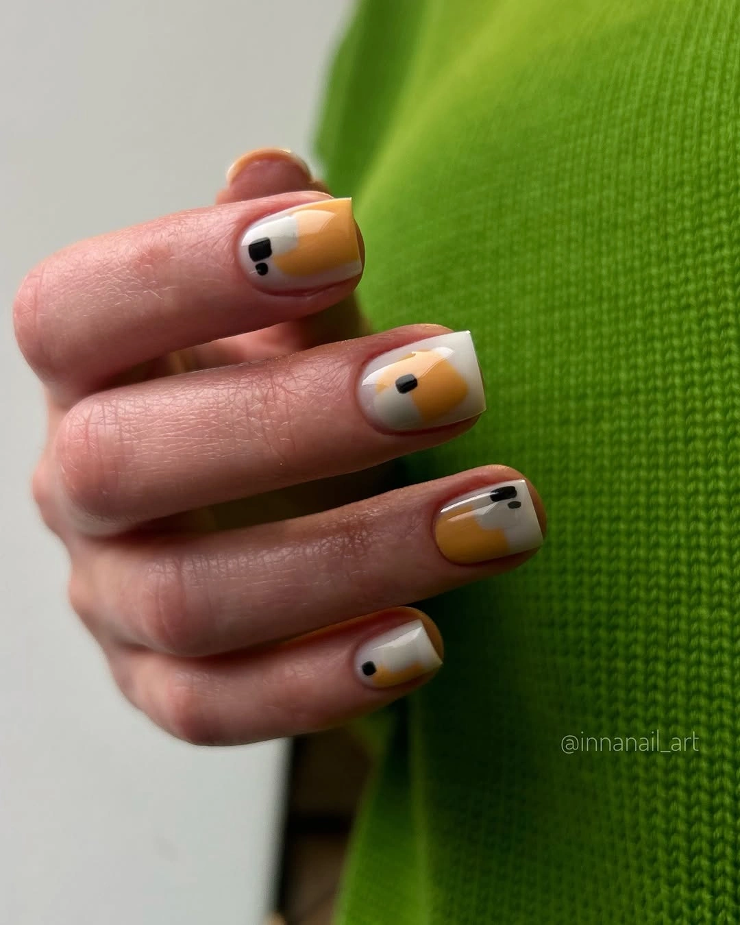 Short square mustard nails with small black blue accents
