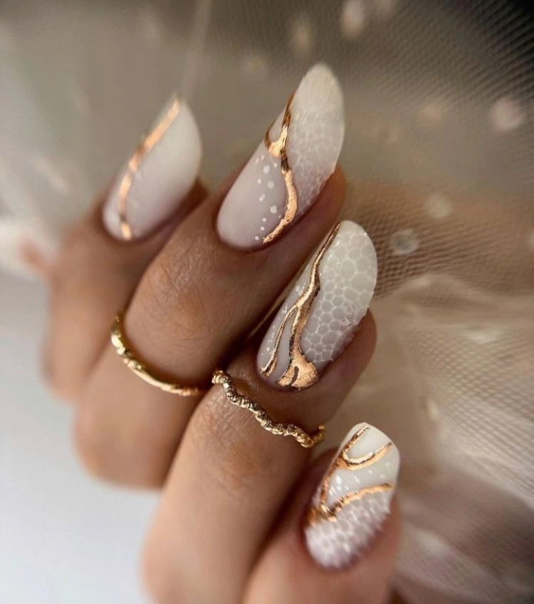 Long pale almond nails with white texture and gold details