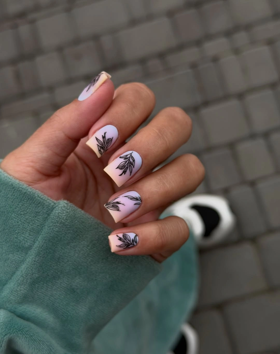 Milky white nails with black botanical leaf drawings