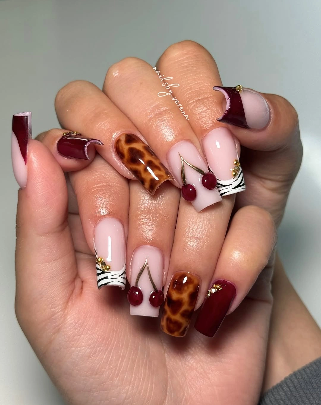 Long almond burgundy nails with nude brown and white accents