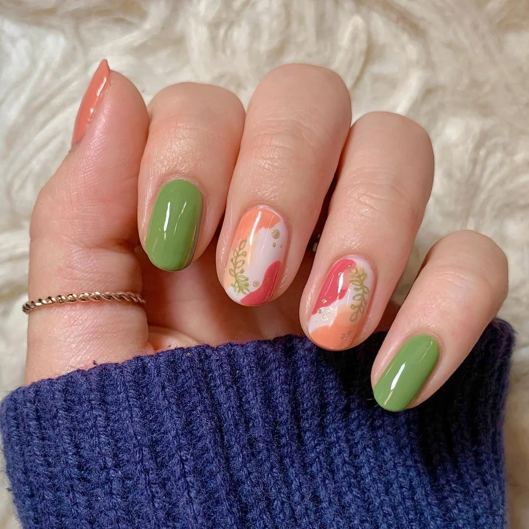Short olive nails with pale accents and tiny warm marks