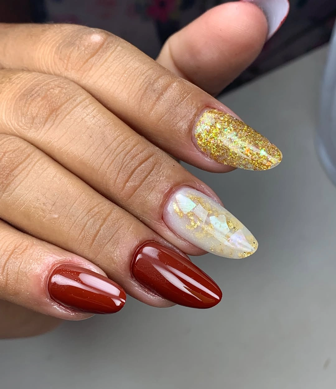 Long red almond nails with pale marble and one bright accent