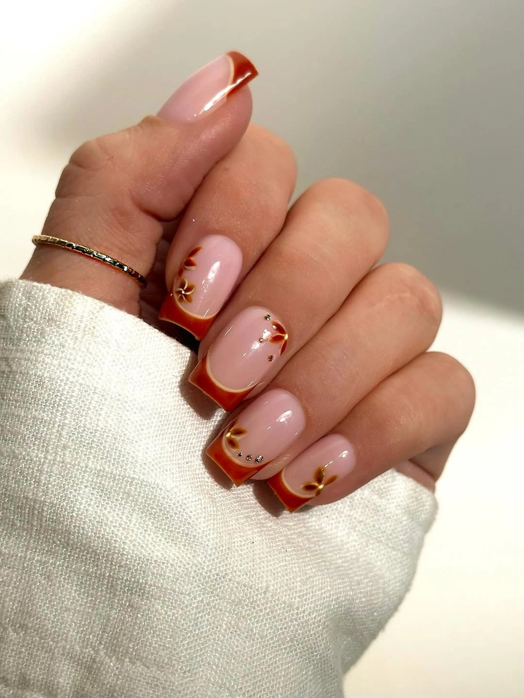 Short pink nails with burgundy curved tips and tiny accents