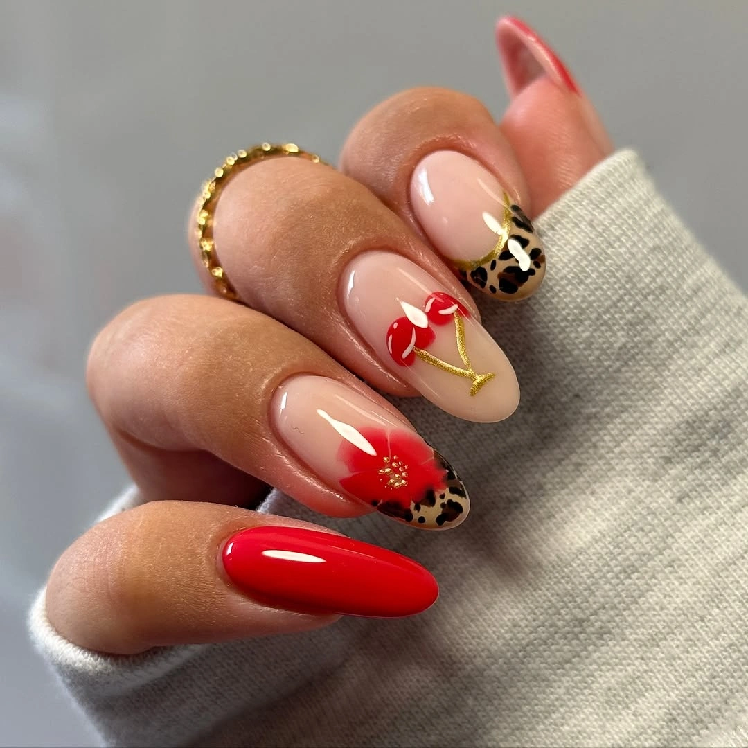 Long red almond nails with nude florals and a dark accent