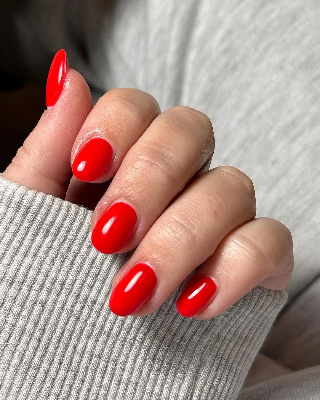 Short rounded nails in a vivid glossy red shade