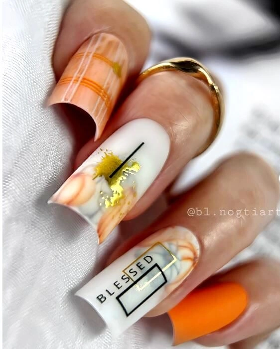 Long square orange nails with pale panels and black graphic marks