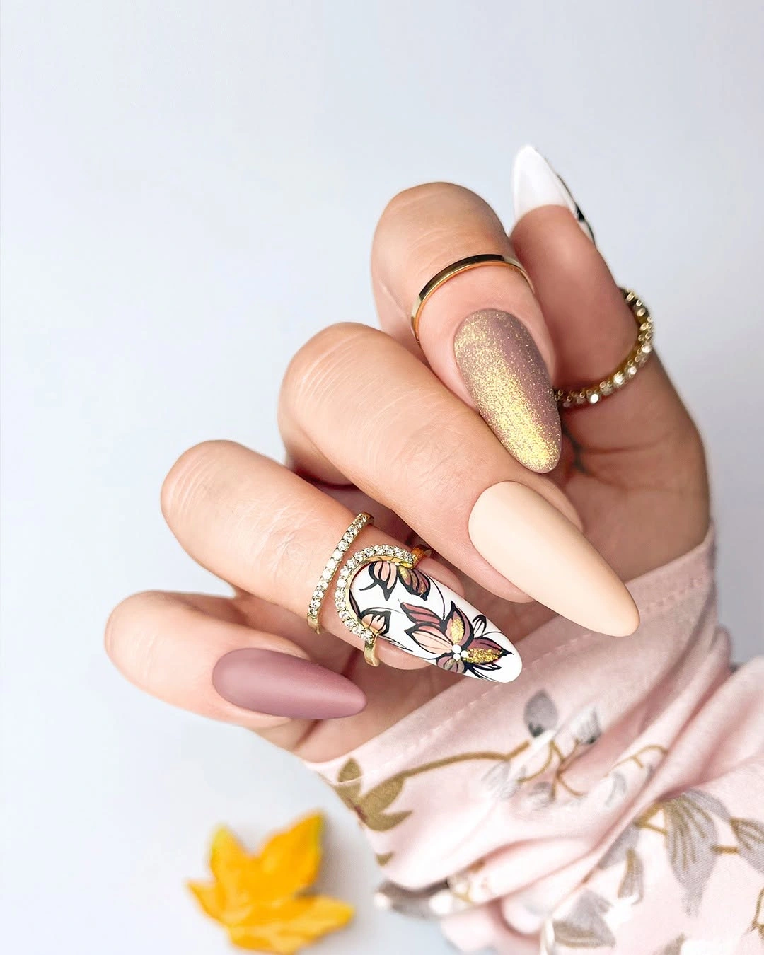 Long neutral almond nails with champagne and black gold floral detail