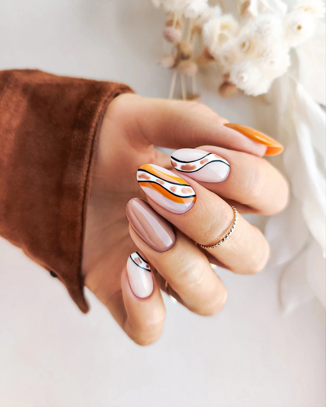 Medium almond nails with orange black and brown contour lines