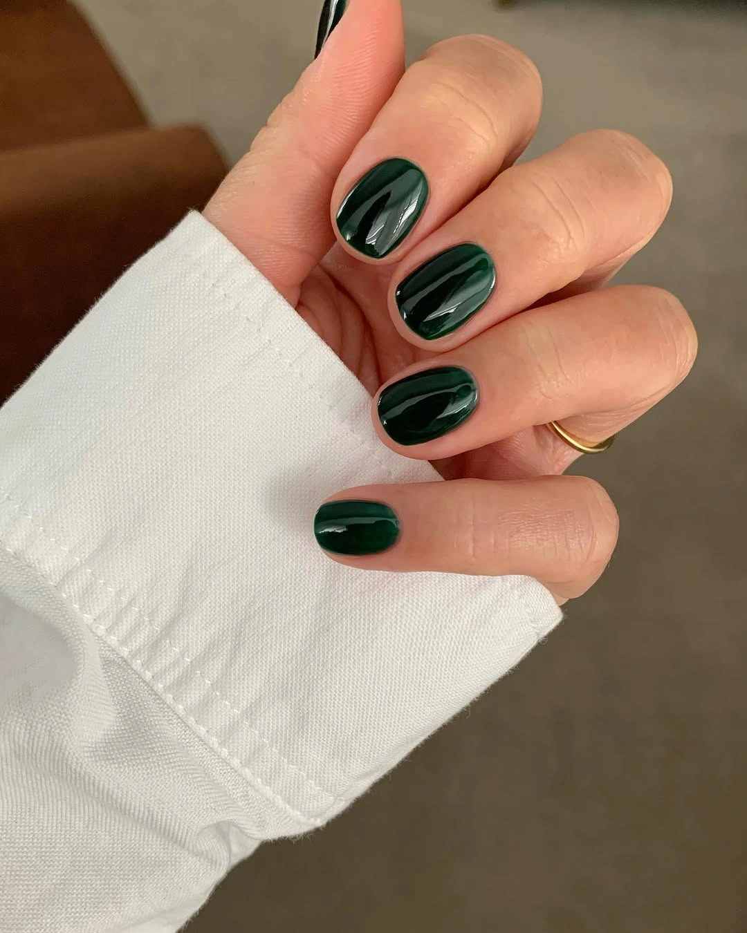 Short glossy deep green nails with subtle curved streaks