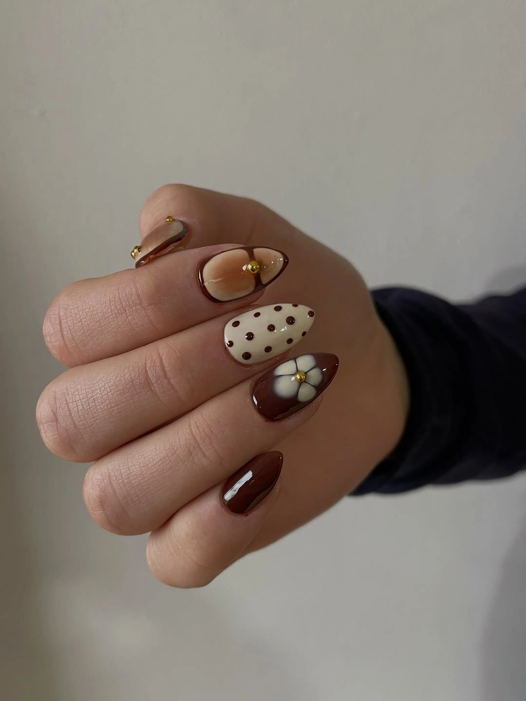 Short brown rounded nails with tiny dots and flower accents