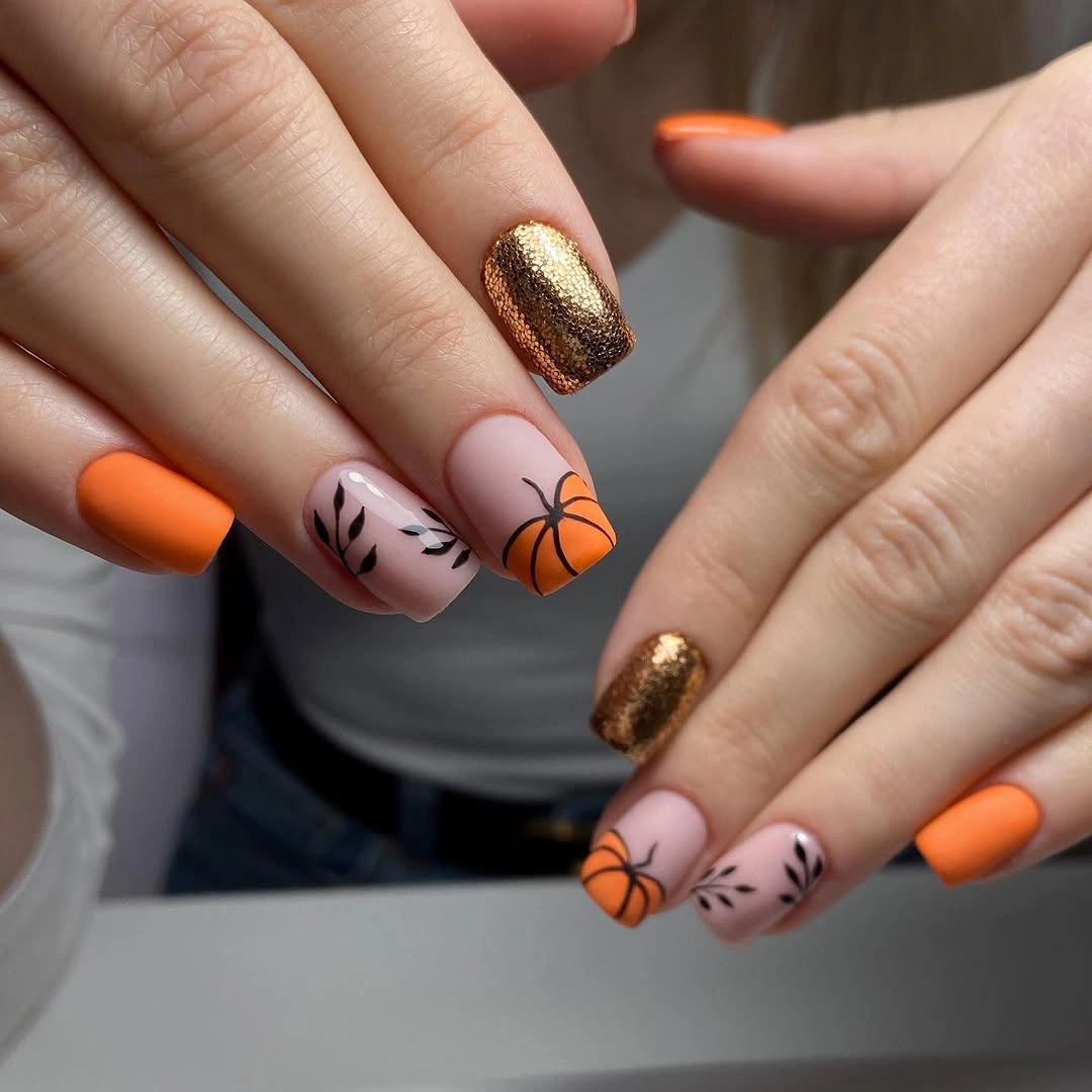 Pink square nails with orange tips and black pumpkin linework