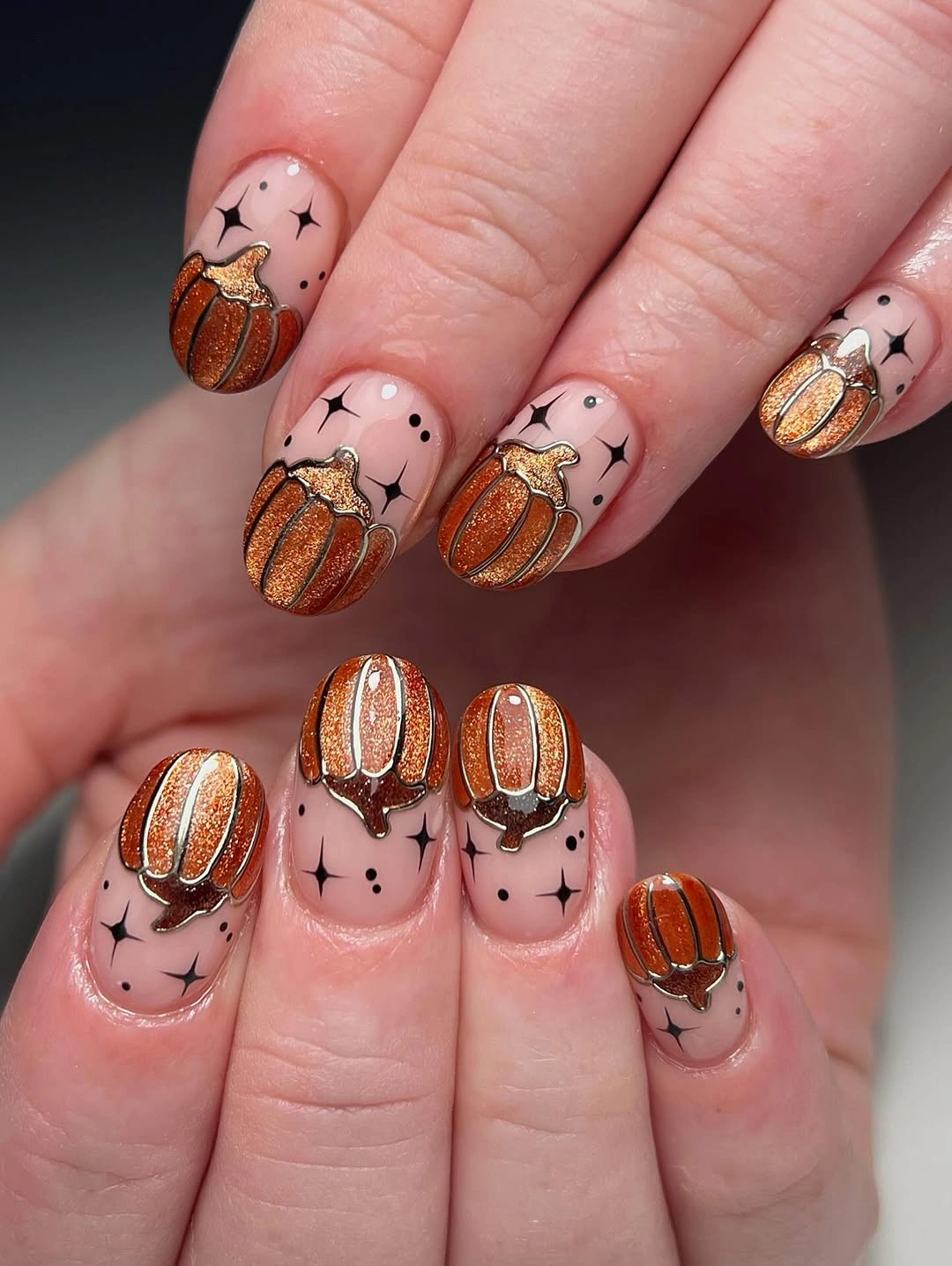 Pale pink nails with orange pumpkin accents and black line details
