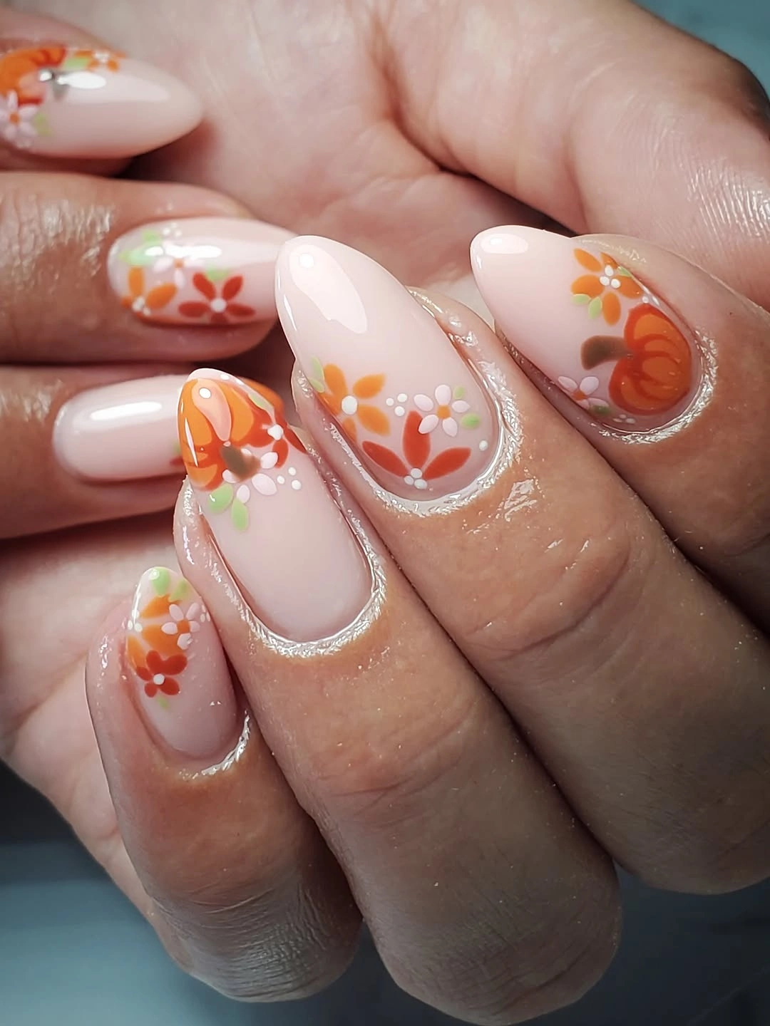 Milky almond nails with orange floral pumpkin accents