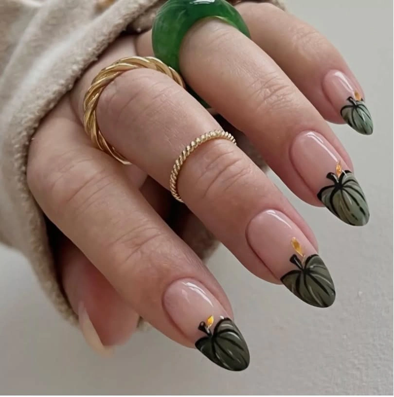 Soft pink almond nails with tiny green pumpkin accents