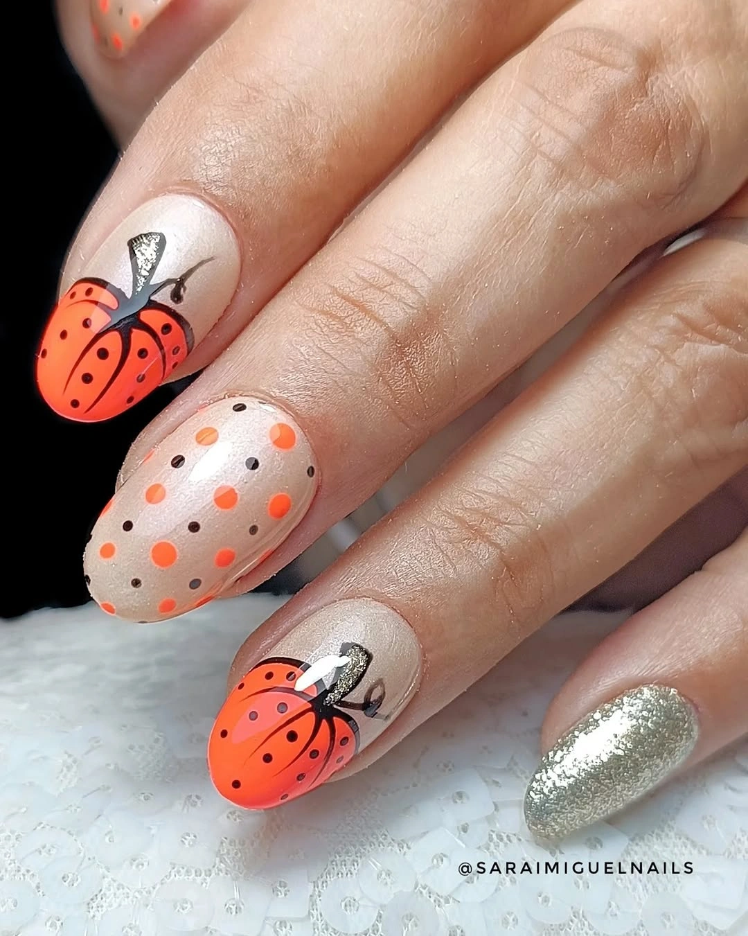 Long almond nails with dotted orange pumpkins and black outlines