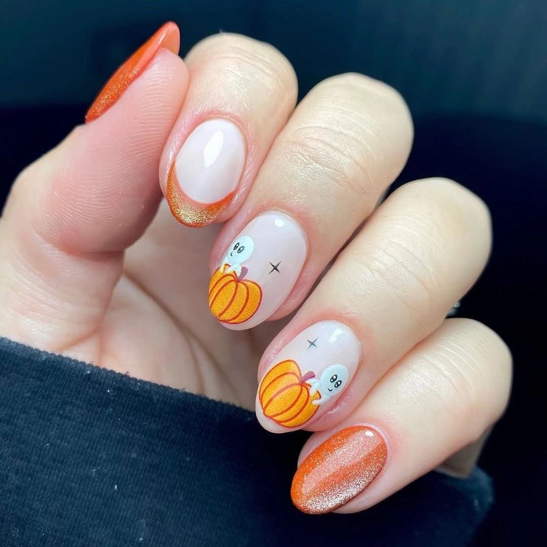 Milky white nails with orange pumpkin outlines and gold accent
