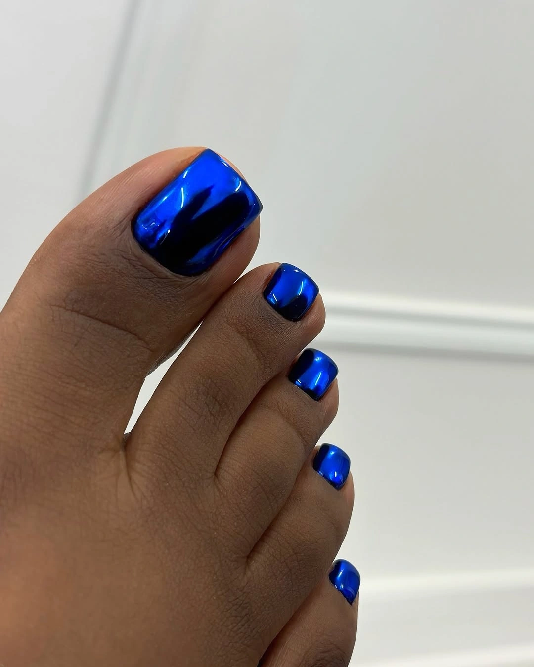 Reflective cobalt blue pedicure on short toenails