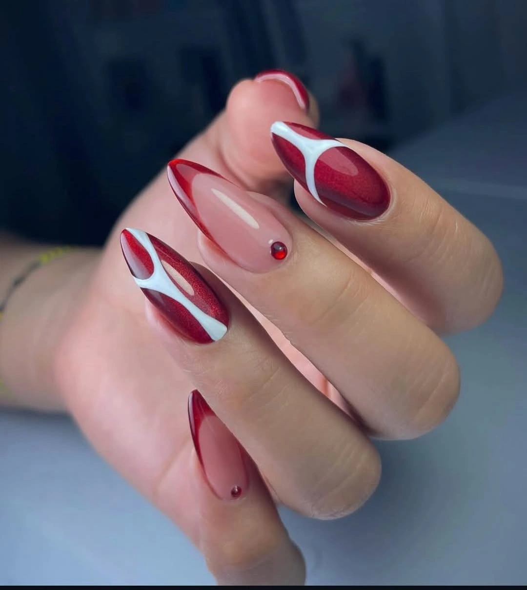 Pointed red and nude nails with white curves