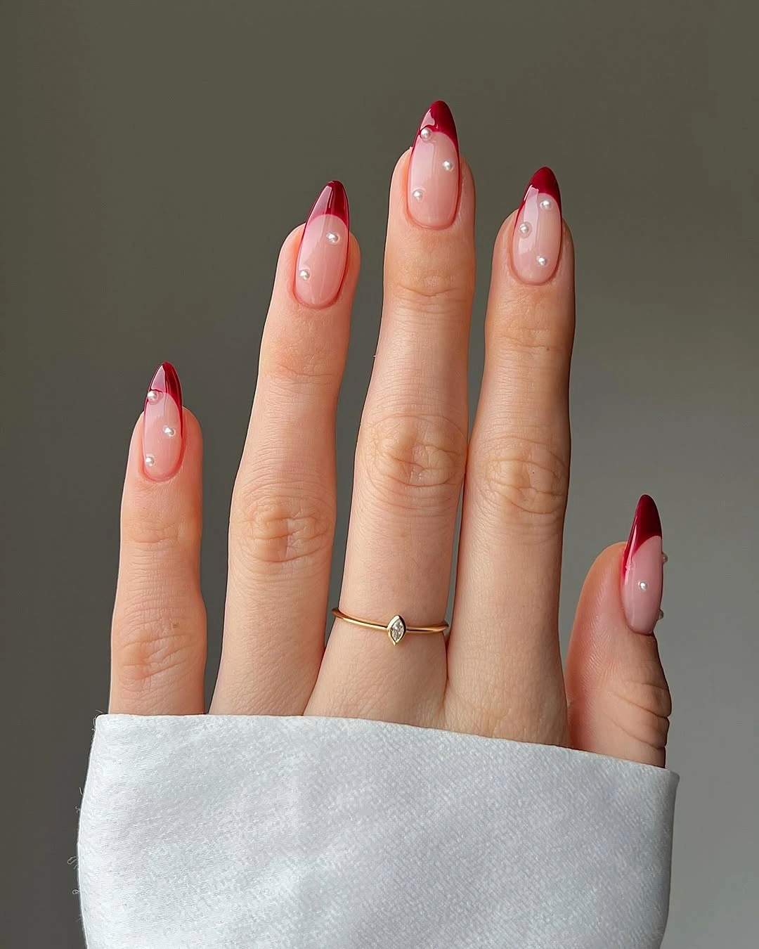 Nude almond nails with red tips and white dots