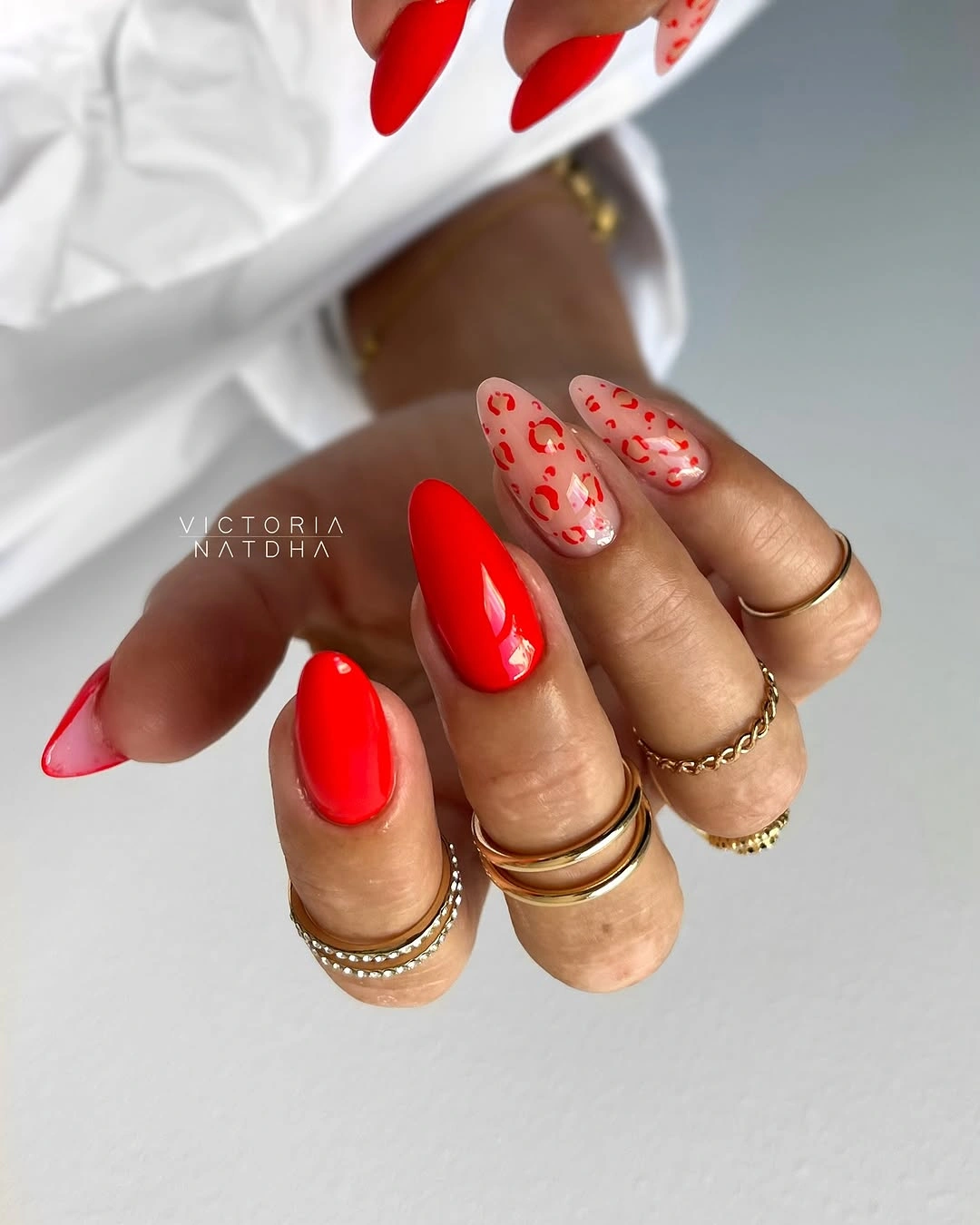 Bright red almond nails with irregular nude accents