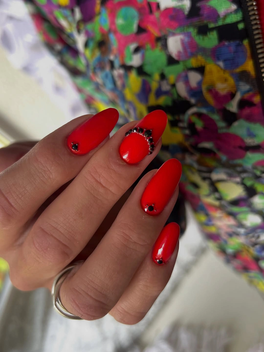 Short glossy red nails with dark dot accents