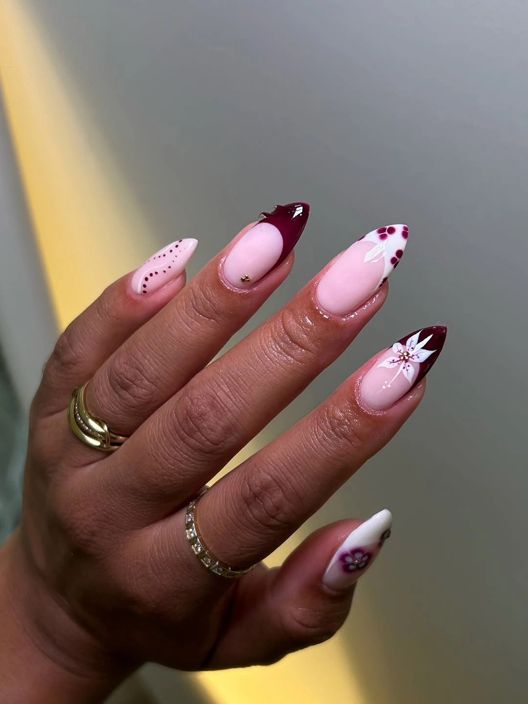 Pale pink almond nails with burgundy tips and dots