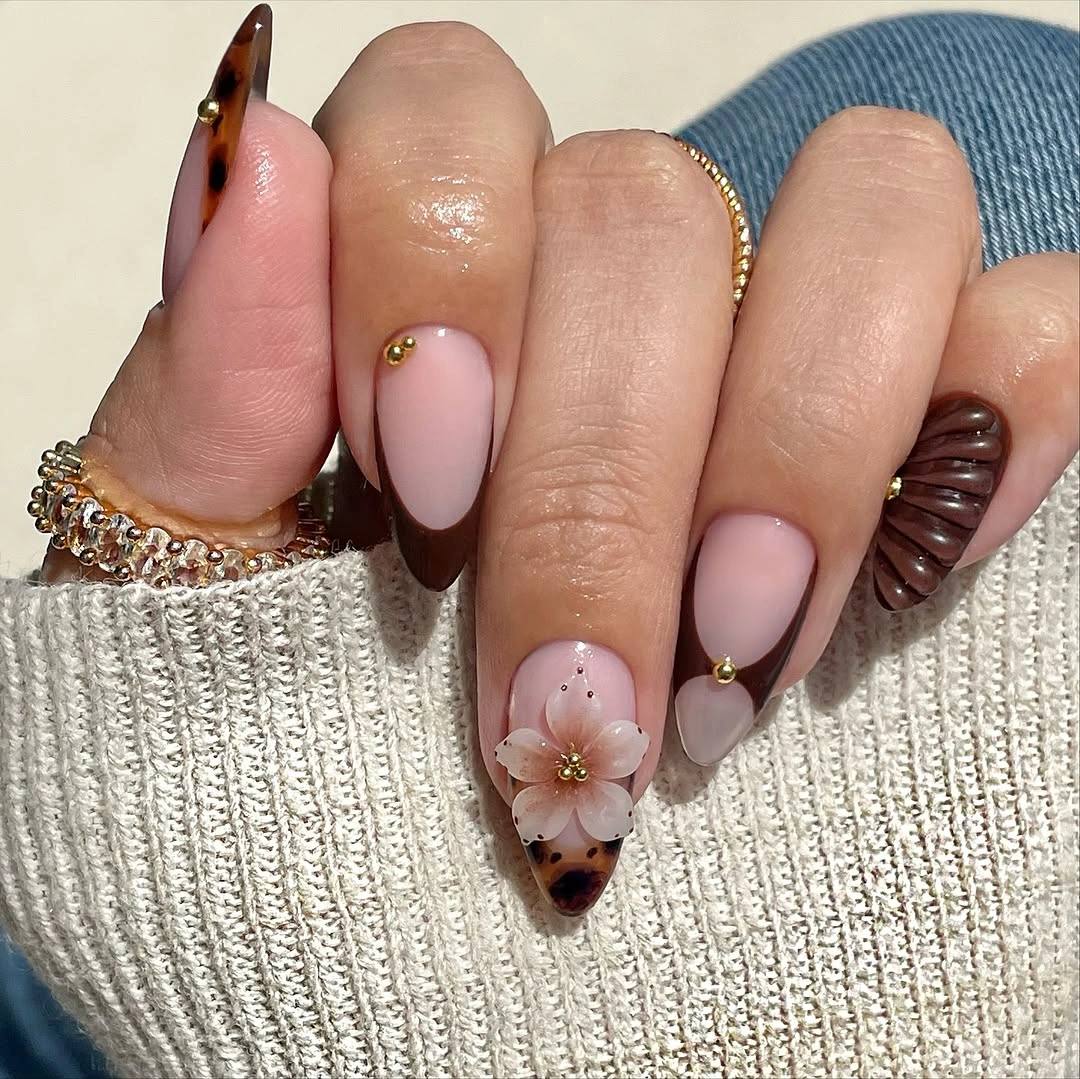 Pale pink almond nails with dark contour lines and floral detail