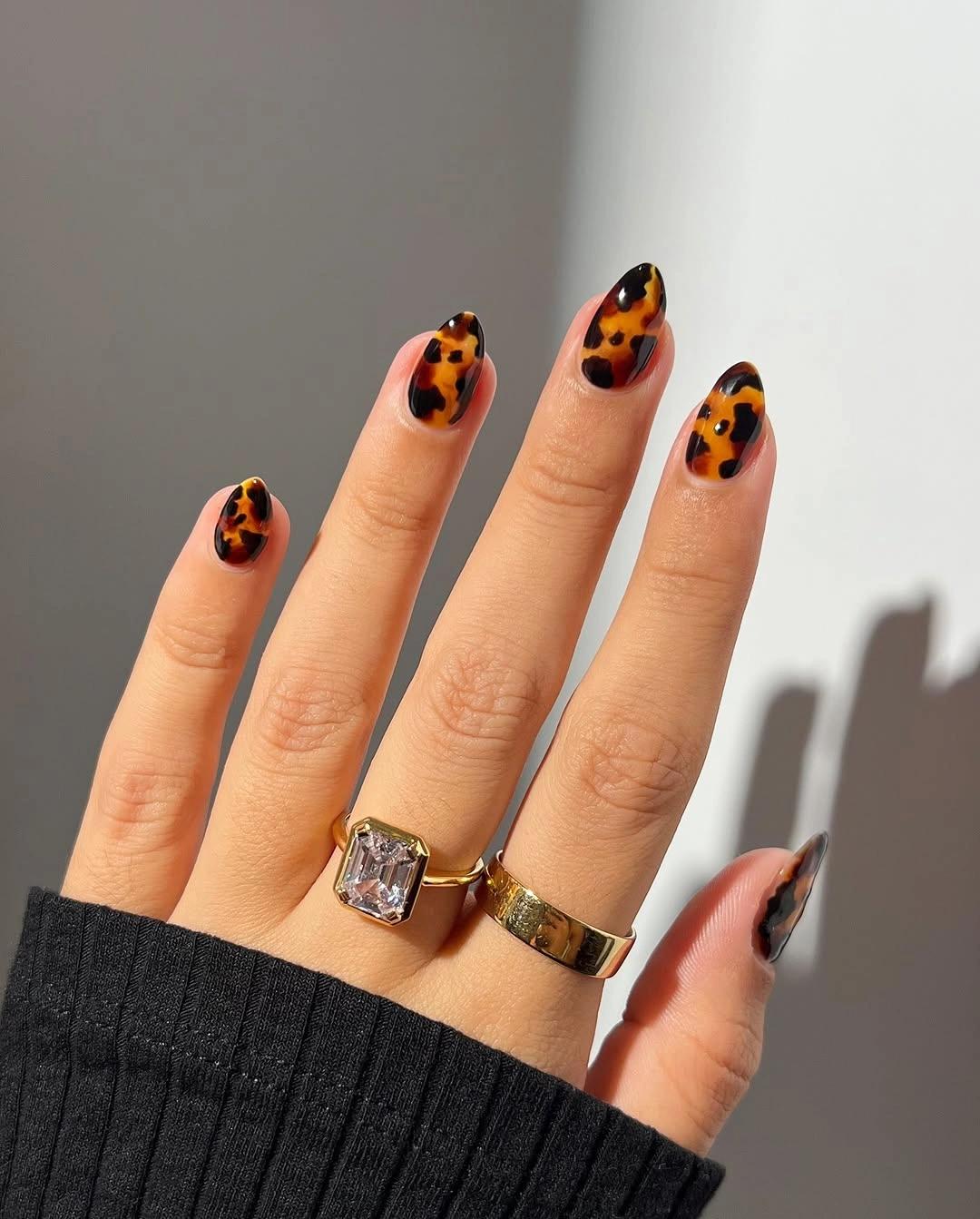 Nude almond nails with orange black spots and a dark tip