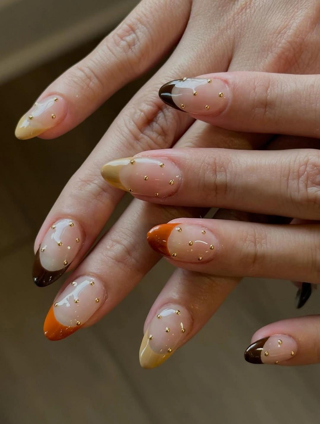Milky almond nails with fine gold dots and warm tip accents