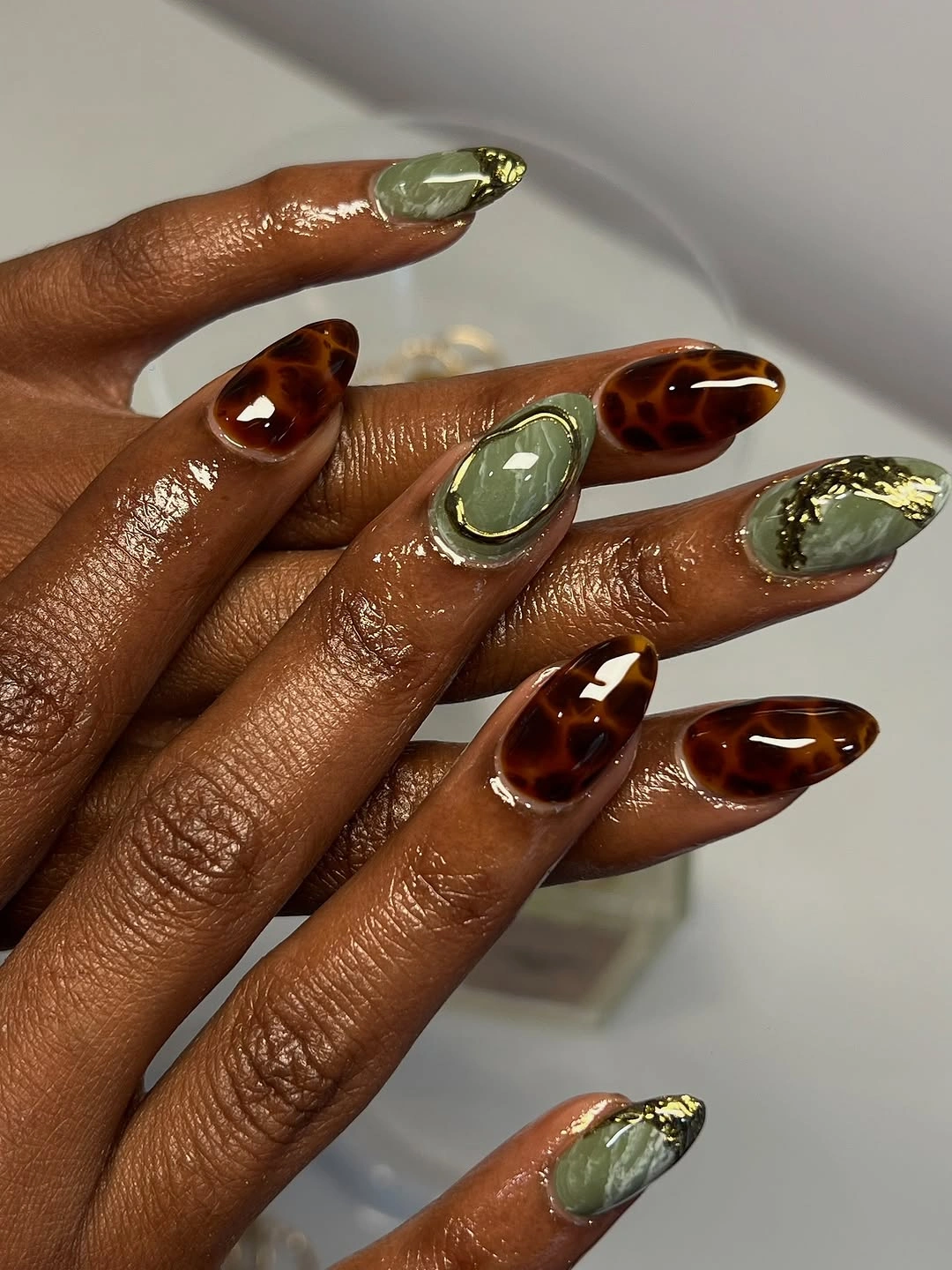 Olive green almond nails with tortoise brown and gold accents