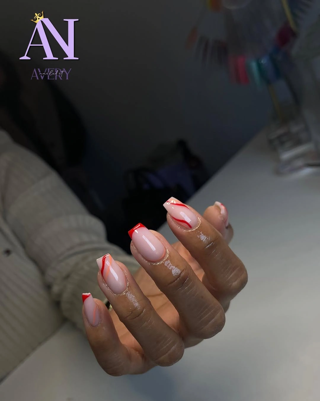Short nude nails with fine red and warm accent lines