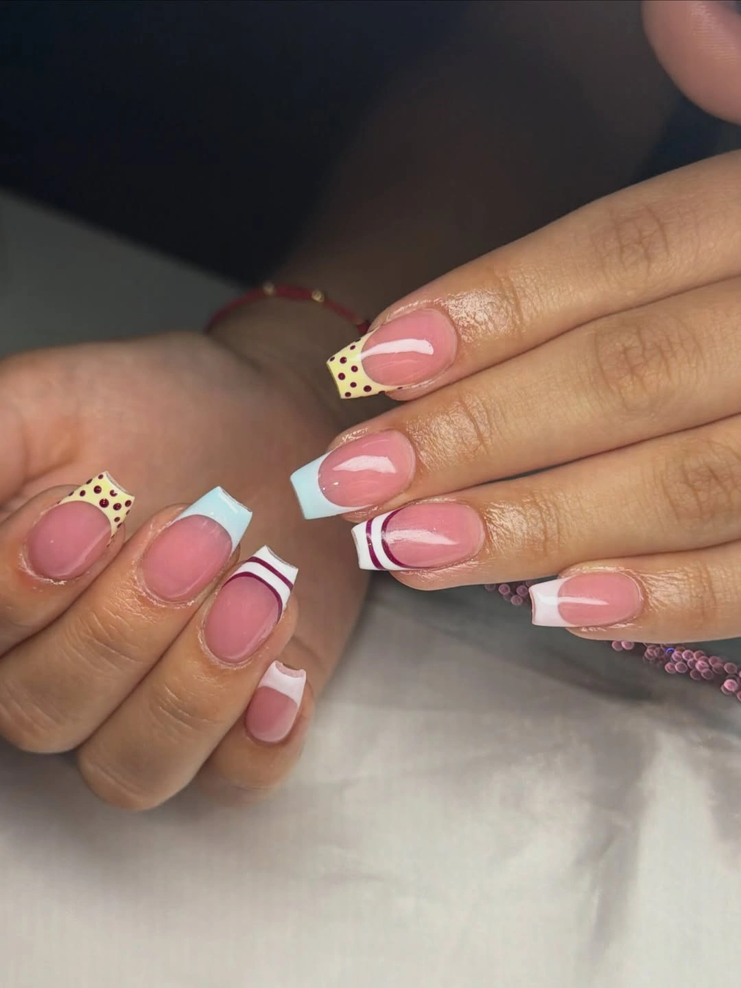 Short pink French nails with white bands and checker accent