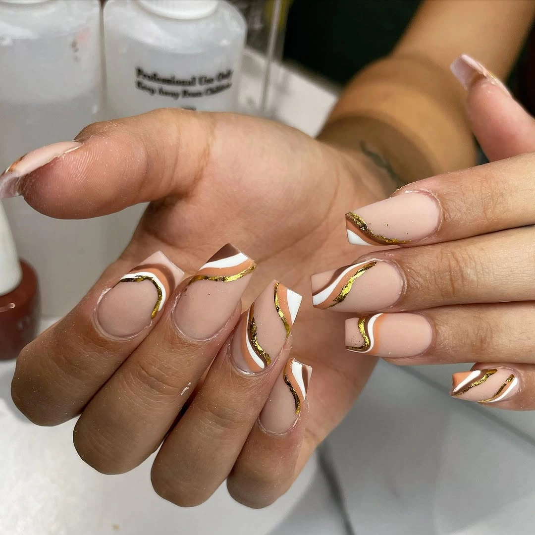 Short nude nails framed with irregular metallic gold lines
