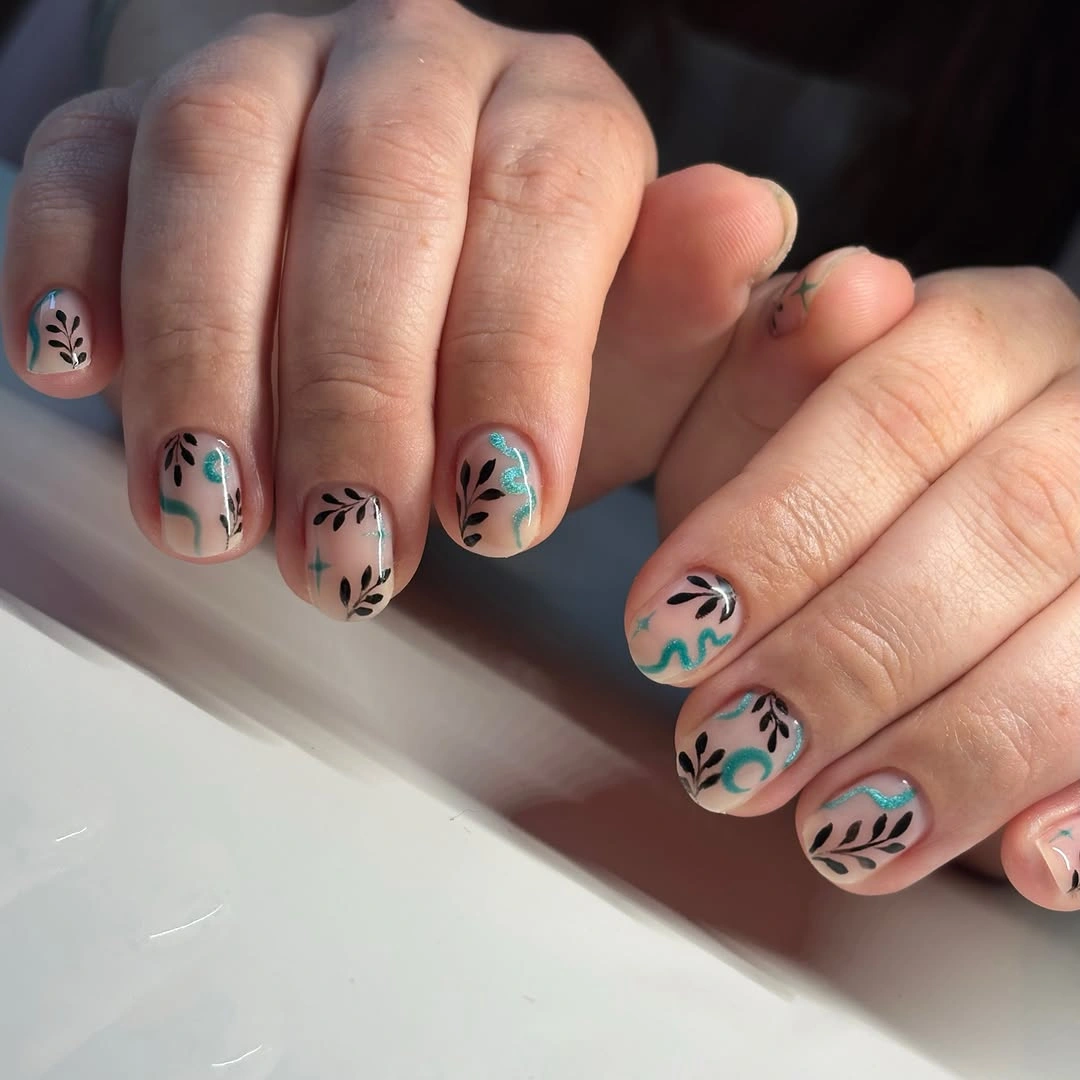 nude short nails with turquoise swirls and black leaves