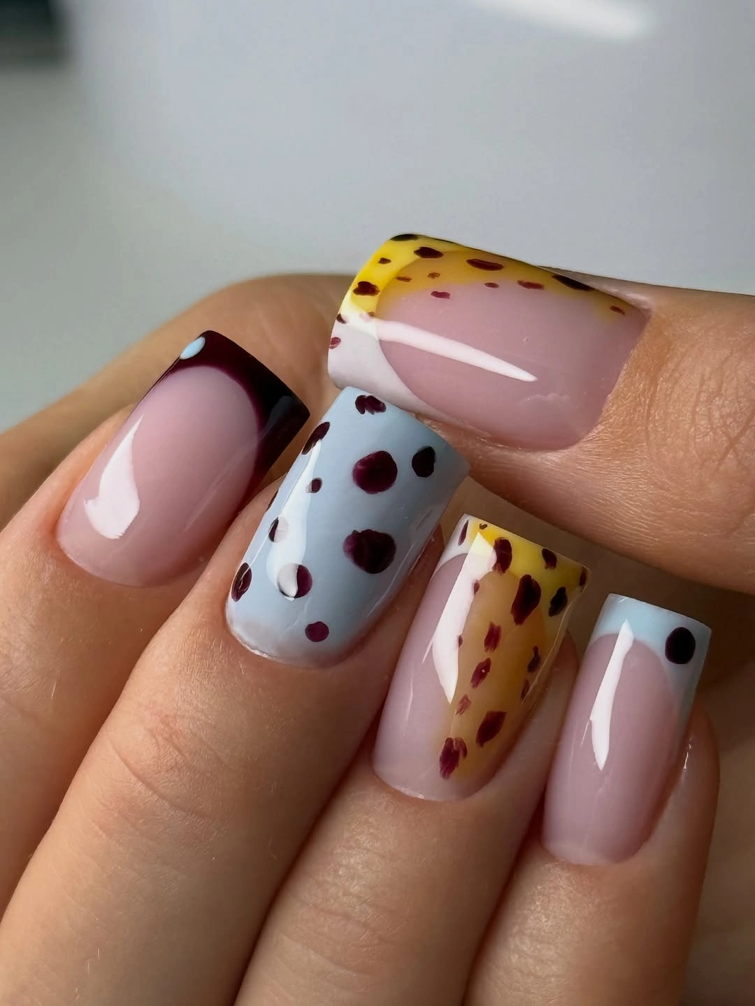 Pale pink square nails with burgundy tips and spotted accents