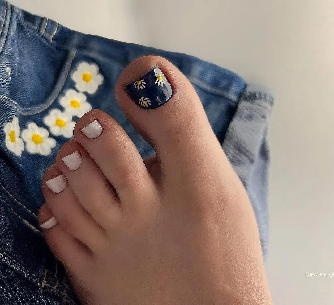 Deep navy big toe with a small white flower and pale toes