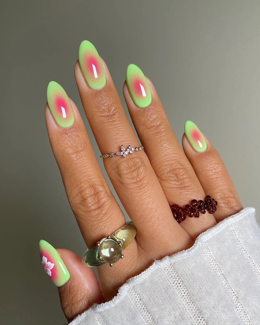 Long almond nails with neon green tips pink accents and a flower