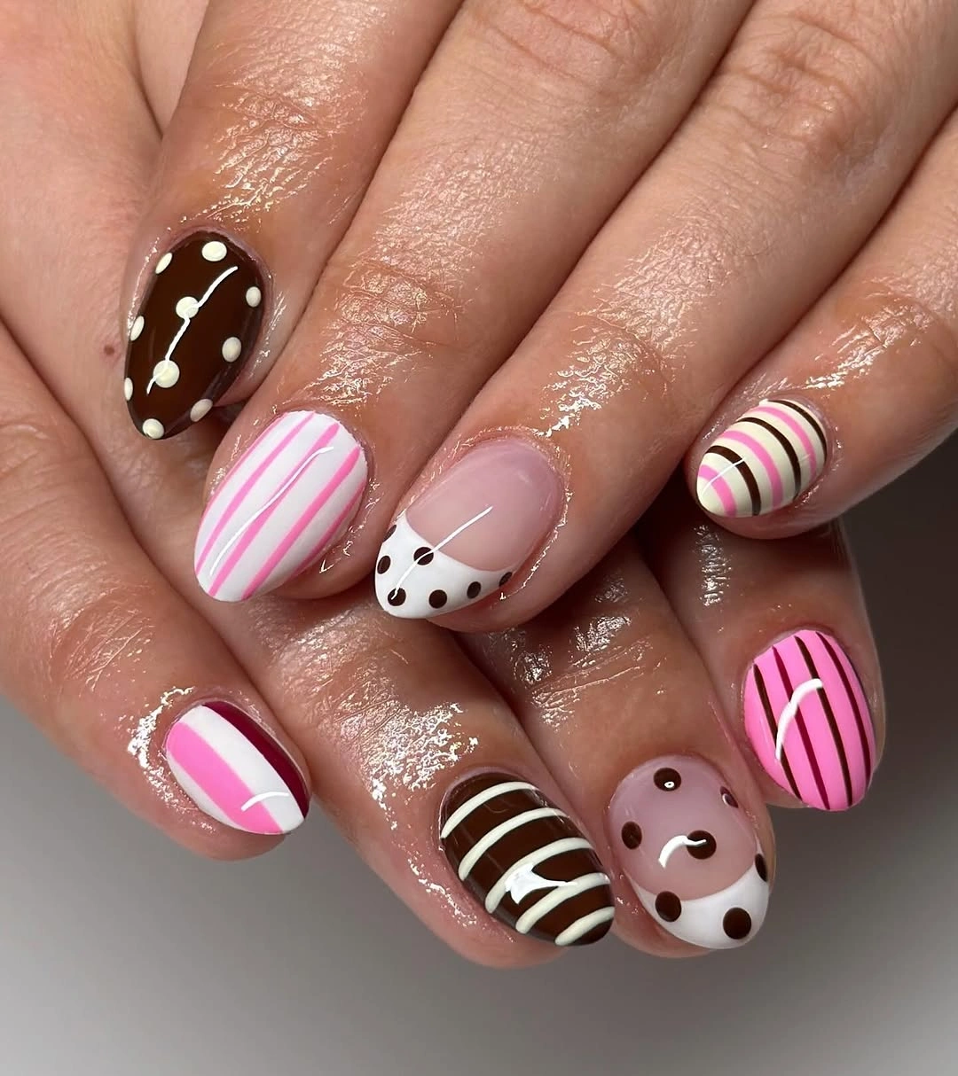 Short rounded nails with pink dots black stripes and tiny motifs