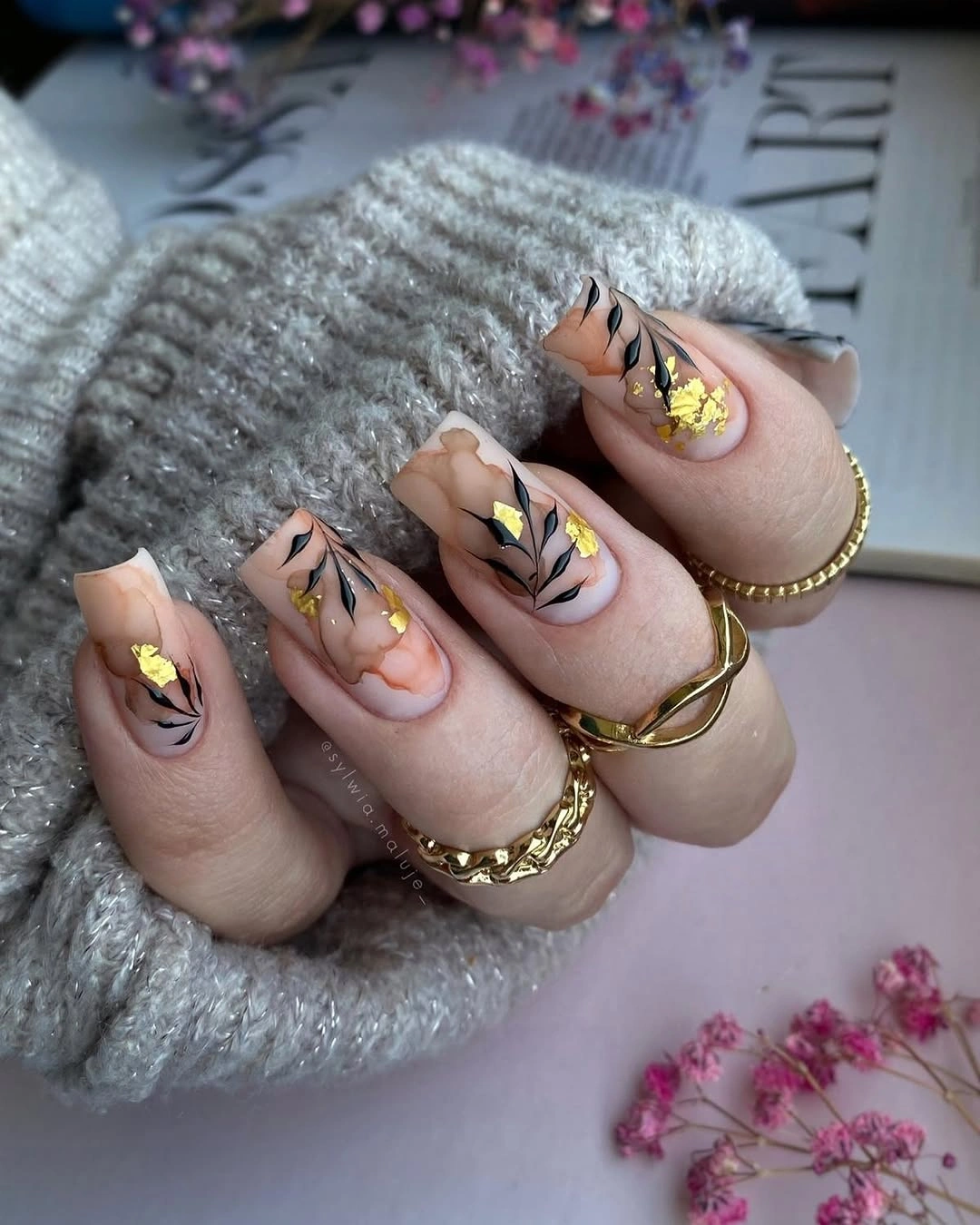 Long nude almond wedding nails with black botanical lines and gold detail