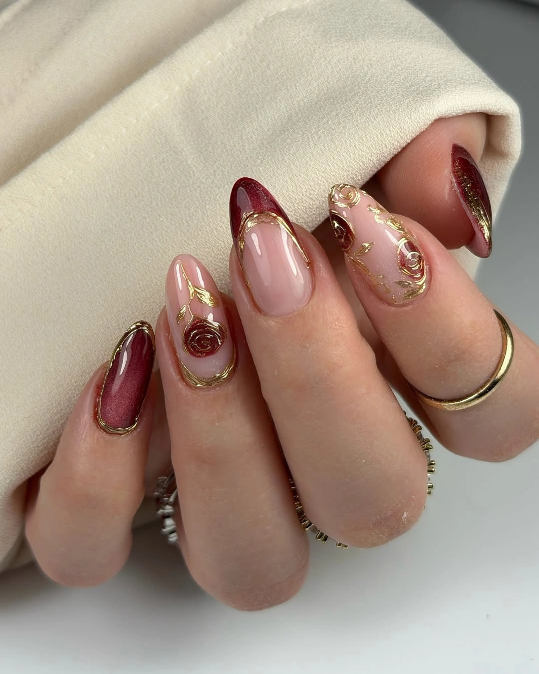 Rose burgundy almond wedding nails with curved metallic details