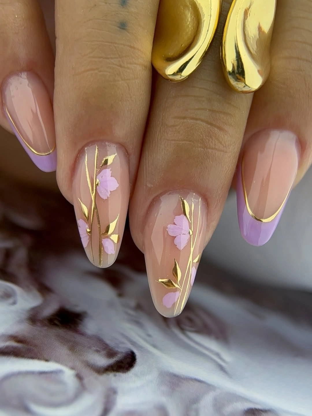 Blush almond wedding nails with lilac flowers and gold stems