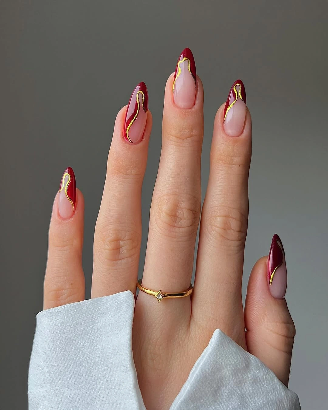Berry red almond wedding nails with curved tips and gold outlines