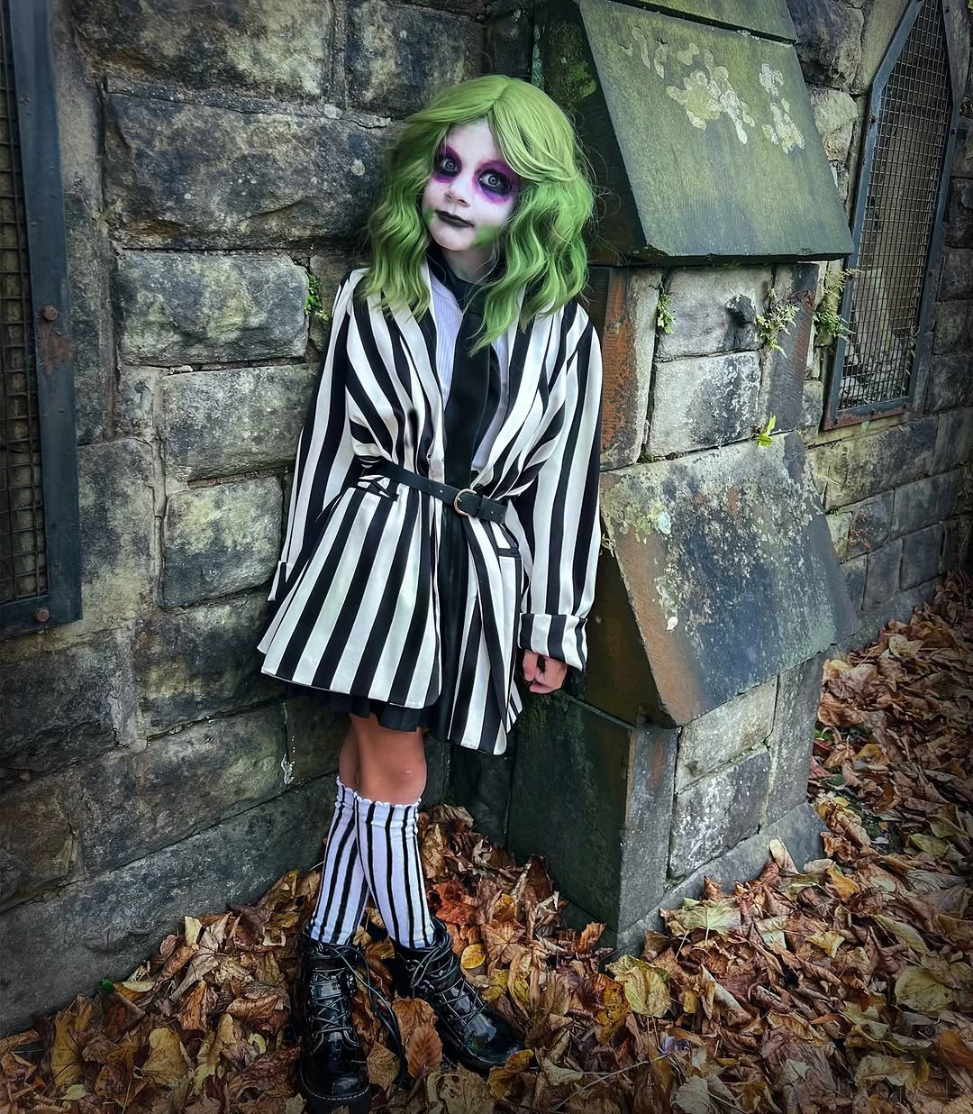 Kids striped black-and-white jacket costume with bright green wig dark boots and pale makeup