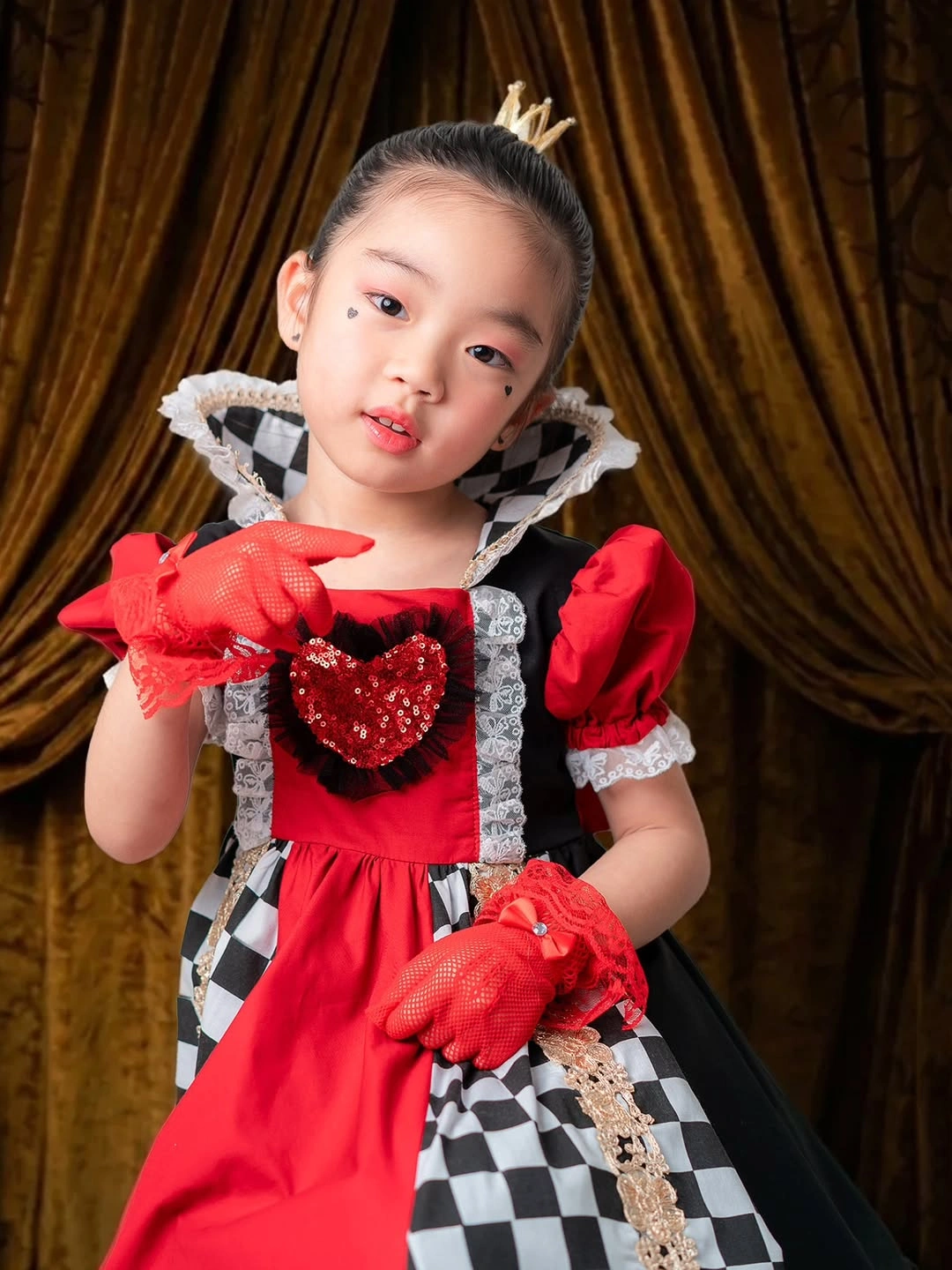 Kids red queen costume with checkerboard panels crown long red gloves and dark details