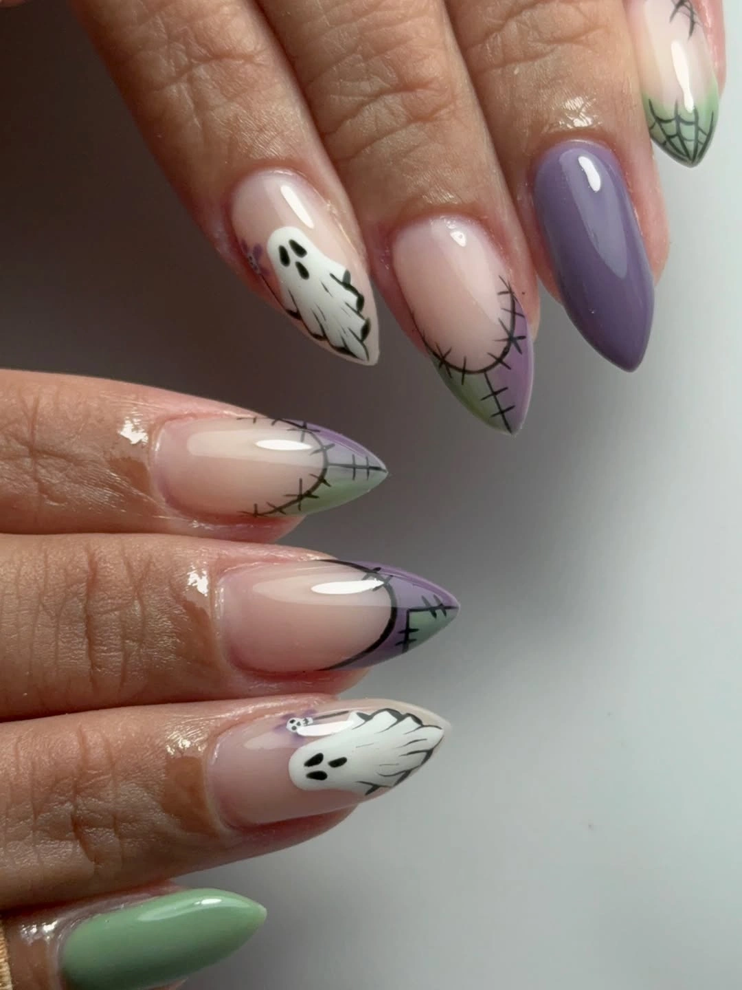 Pastel almond nails with tiny ghosts stitches and green accent