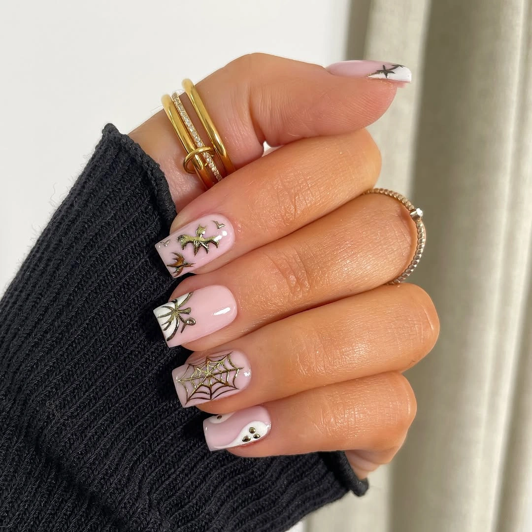 Nude almond nails with tiny ghosts webs and muted orange details