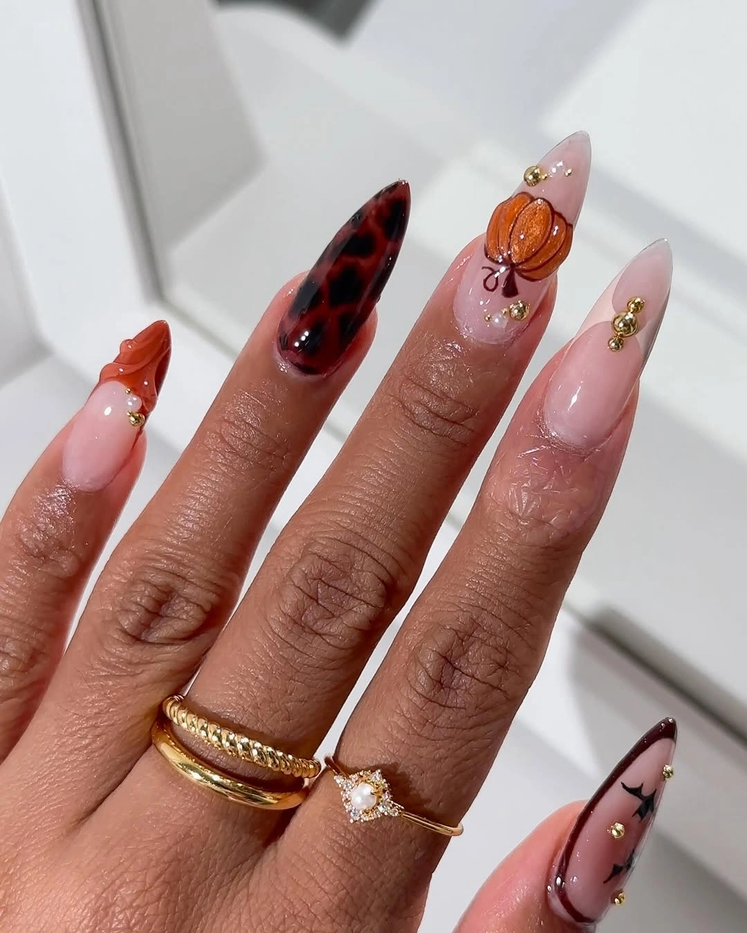 Nude pink stiletto nails with tortoise orange and spider accents