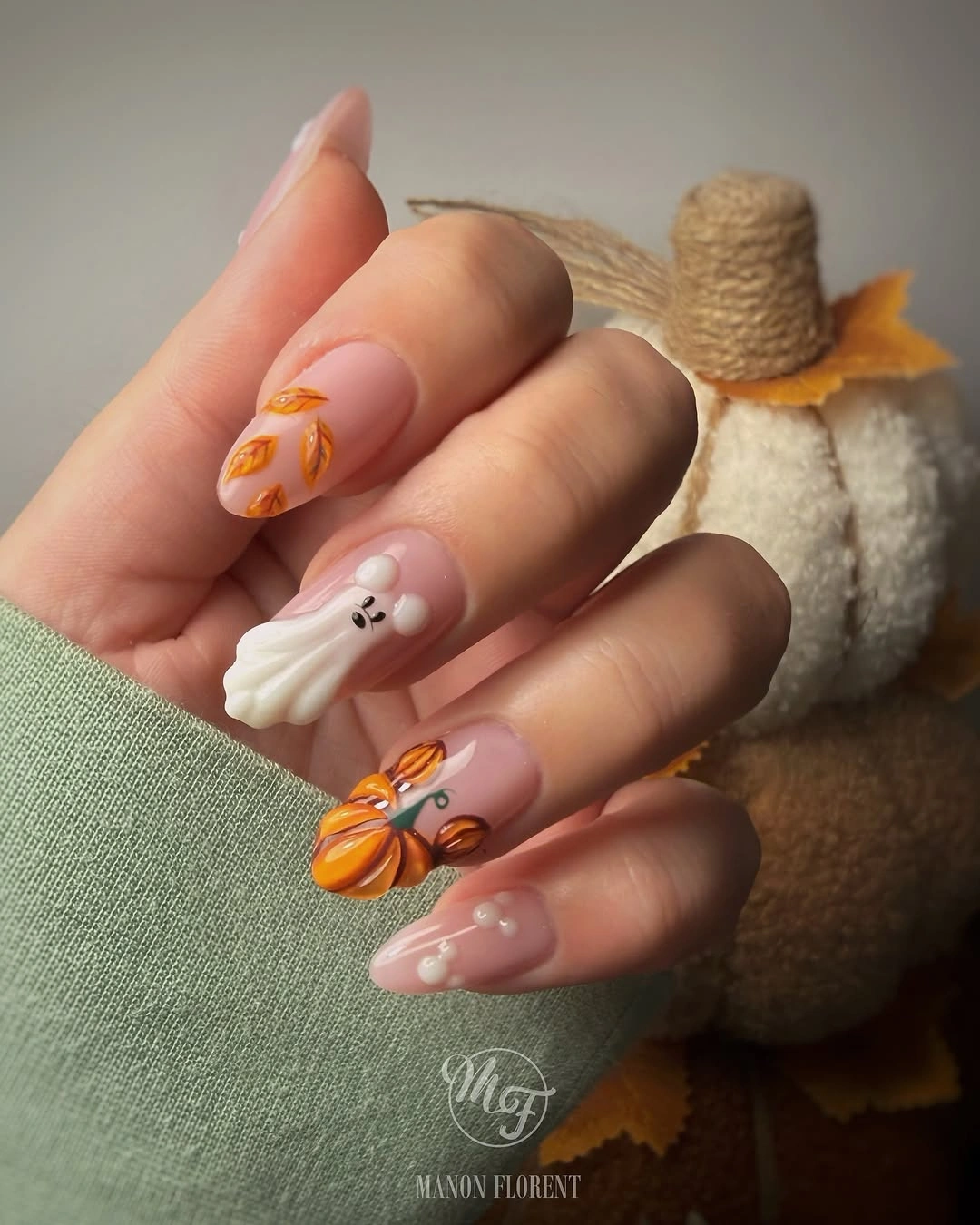 Medium nude almond nails with small pumpkin and ghost accents
